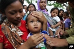 FILE - An Indonesian child receives a shot of measles vaccine in Banyusoco village near Gunung Kidul, Indonesia.