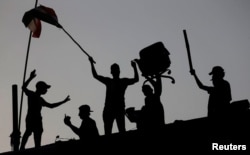 Iraqi protesters stand on concrete blast walls during an anti-government protest near a government building in Basra, Iraq, Sept. 7, 2018.