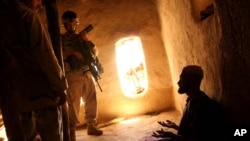 FILE - U.S. Army soldier and an Afghan translator interrogate person in the Bagh village of Khakeran Valley, Zabul province, Afghanistan, June 2005.