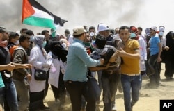 Palestinian protesters evacuate a wounded youth near the Israeli border fence, east of Khan Younis, in the Gaza Strip, May 14, 2018.