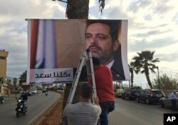 Workers hang a poster of outgoing Prime Minister Saad Hariri with Arabic words that read "We are all Saad," on a seaside street in Beirut, Lebanon, Nov. 9, 2017.
