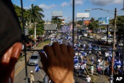 FILE - An individual watches from above as people march in an anti-government protest in Managua, Nicaragua, Aug. 11, 2018. The current unrest began in April, when President Daniel Ortega imposed cuts to the social security system.