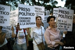 FILE - People hold placards at a rally to pay tribute to victims of violence in protests against Venezuelan President Nicolas Maduro's government, in Caracas, Venezuela, Aug. 30, 2017. The placards read "Political prisoner".