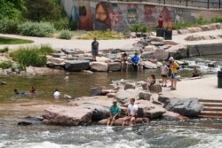 People cool off in the water at the confluence of the South Platte River and Cherry Creek in Denver, Wednesday June 16, 2021. A heat wave continues to hover over the western U.S., pushing the temperature to 99 degrees in Denver. (AP Photo/Brittany Peterso