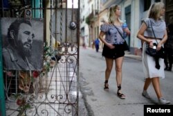 Tourists walk past an image of Cuba's late president Fidel Castro in downtown Havana, Cuba, Nov. 11, 2017.