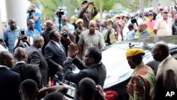 FILE - Zimbabwe President Emmerson Mnangagwa, center, leaves after paying his respects to the family of Morgan Tsvangirai, in Harare, Feb. 18, 2018.