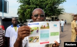 A health care worker displays an Ebola information leaflet for passengers at Ngobila Beach in Kinshasa, Democratic Republic of Congo, May 24, 2018. Congo's fight to rein in a deadly Ebola outbreak has authorities crossing the border to buy up available thermometers.
