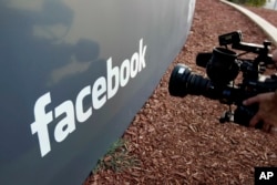 FILE - A television photographer shoots the sign outside of Facebook headquarters in Menlo Park, Calif., May 18, 2012.