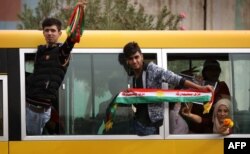 FILE - Iraqi Kurds wave fabric strips in the colors of the Kurdish flag during a rally in support of Iraqi Kurdish leader Masoud Barzani, in Irbil, Iraqi Kurdistan, Oct. 30, 2017.