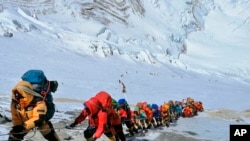 In this May 22, 2019 photo, a long queue of mountain climbers line a path on Mount Everest just below camp four, in Nepal.