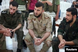 Zahran Alloush, center, commander of Army of Islam, sits during a conference in the town of Douma, eastern Ghouta in Damascus, Syria, Aug. 27, 2014.