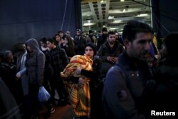 Refugees and migrants arrive aboard the passenger ferry Nissos Rodos at the port of Piraeus, near Athens, Greece, Jan. 13, 2016.