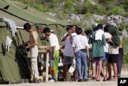 FILE - Men shave, brush their teeth and prepare for the day at a refugee camp on the Island of Nauru, Sept. 21, 2001.