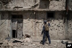 Iraqi policeman spray paint a house exterior to warn that it is booby trapped during fighting against Islamic State militants in the Old City of Mosul, Iraq, June 26, 2017.