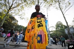 Seorang penjual menjajakan ikat kepala selama berlangsungnya aksi protes terhadap rencana pemilu di Kuala Lumpur, Malaysia, Rabu, 28 Maret 2018.