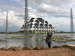 Seorang perempuan berfoto di Embung Gedebage, Kota Bandung, yang berdampingan dengan Masjid Raya Jawa Barat. Embung ini dibuat untuk kendalikan air di Bandung Raya bersama sejumlah proyek lainnya. (VOA/Rio Tuasikal)