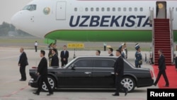FILE - Chinese guards walk alongside the car of Uzbekistan President Shavkat Mirziyoyev in Qingdao city, Shandong province, China, June 8, 2018.