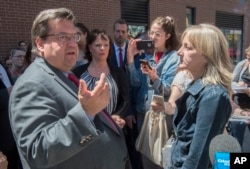 A resident (right) confronts Montreal's Mayor Denis Coderre and Lucie Charlebois (center) Minister for Rehabilitation, Youth Protection, Public Health and Healthy Living, June 26, 2017, during the inauguration of a "safe injection site."