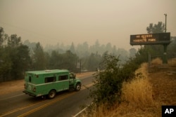 FILE - A fire transport drives along Highway 140, one of the entrances to Yosemite National Park, in Mariposa, Calif., July 16, 2018.