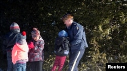 A Royal Canadian Mounted Police officer assists a child from a family that claimed to be from Sudan as they walk across the U.S.-Canada border into Hemmingford, Canada, from Champlain, New York, Feb. 17, 2017.