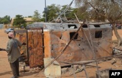 A woman reacts beside a burnt container after a suicide car bomb attack overnight in Gao, Nov. 13, 2018.