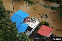 FILE - People wait for aid on the roof of their house at a flooded area in the southern state of Kerala, India, Aug. 17, 2018.