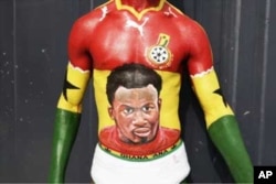 A Ghanaian football fan shows off his body painting, containing the image of star player Michael Essien
