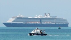 A speed boat, foreground, transports samples from some passengers who have reported stomachaches or fever, in the Westerdam, seen in the background, off Sihanoukville, Cambodia, Feb. 13, 2020.