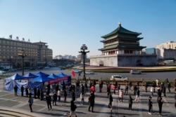 In this photo released by China's Xinhua News Agency, residents line up for tests at a COVID-19 testing site in Xi'an in northwestern China's Shaanxi Province, Dec. 21, 2021.
