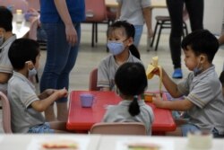 Pre-school children gather around a table inside their classroom as schools reopened in Singapore on June 2, 2020, as the city state eased its partial lockdown imposed to prevent the spread of COVID-19 in Singapore. (Photo by ROSLAN RAHMAN / AFP)