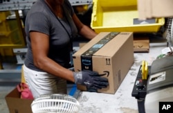 FILE - An Amazon employee applies tape to a package before shipment at an Amazon fulfillment center in Baltimore, Maryland, Aug. 3, 2017.