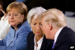 FILE - German Chancellor Angela Merkel watches as President Donald Trump talks with IMF Managing Director Christine Lagarde during the Gender Equality Advisory Council breakfast during the G-7 summit in Charlevoix, Canada, June 9, 2018.