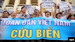 Vietnamese protesters hold a large banner reading 'Vietnam People Save The Sea' during a rally denouncing recent mass fish deaths in Vietnam's central province, in Hanoi, Vietnam, May 1, 2016.