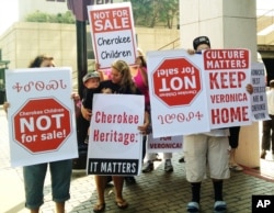 File photo shows Cherokee tribe members protesting the adoption of a 3-year-old Cherokee girl by a non-Native couple, Wednesday, Aug. 14, 2013 in Tulsa, OK.