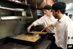 Sous chefs Adan Franco, right, and Casey Davison of the Sanford Restaurant season and stir cassoulet, to be delivered to the Guest House homeless shelter in Milwaukee, Dec. 8, 2015.