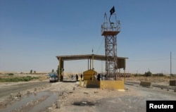 Islamic State militants stand guard after controlling a checkpoint in Khazer at the border area of the Kurdish semi-autonomous region, Aug. 7, 2014.