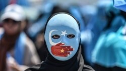 A demonstrator wearing a mask painted with the colours of the flag of East Turkestan and a hand bearing the colours of the Chinese flag attends a protest of supporters of the mostly Muslim Uighur minority and Turkish nationalists to denounce China's treat