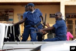 FILE - Police drive by the scene of a grenade attack on a parked car downtown Bujumbura, July 20, 2015.