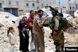 Israeli soldiers stop Palestinians at the entrance of Yatta near the West Bank city of Hebron June 9, 2016.