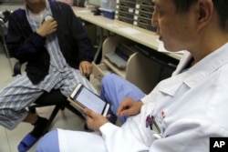 Dr. Li Dianyou uses a tablet computer to adjust the settings of a deep brain stimulation device implanted in the brain of a methamphetamine user named Yan, left, on Monday, Oct. 29, 2018, at Ruijin Hospital in Shanghai, China.