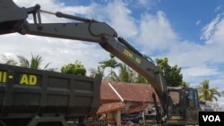 Petugas mengoperasikan alat berat untuk membersihkan reruntuhan dan mencari korban (VOA/Bhagaskoro).