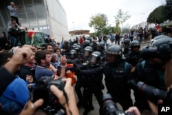 Civil guards clear people away from the entrance of a sports center, assigned to be a polling station by the Catalan government and where Catalan President Carles Puigdemont is expected to vote, in Sant Julia de Ramis, near Girona, Spain, Oct. 1, 2017.