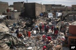 FILE - Civil protection rescue teams work on the debris of a destroyed house to recover the body of people killed during fighting between Iraqi security forces and Islamic State militants on the western side of Mosul, Iraq, March 24, 2017.