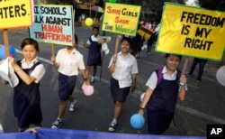 FILE - School girls holding placards react to camera as they walk as part of an awareness campaign against human trafficking in Kolkata, India, Feb. 15, 2015.