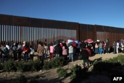 Residents of Anapra, a neighborhood on the outskirts of Ciudad Juarez in Mexico, gather next to the border fence during a prayer with priests and bishops from Mexico and the United States on Feb. 26, 2019.