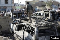 A Houthi fighter walks on a vehicle damaged by an air strike at a residential area near Sanaa Airport March 26, 2015. REUTERS/Khaled Abdullah