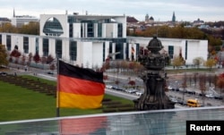 FILE - A German national flag flutters in front of the Chancellery in Berlin. The 2013 revelation that the U.S. National Security Agency had tapped German Chancellor Angela Merkel's mobile phone came from WikiLeaks.