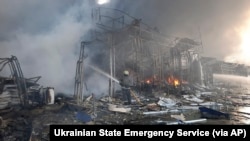 In this photo released by the Ukrainian State Emergency Service press service, firefighters work to extinguish a fire at a market hit by shelling in Kharkiv, Ukraine, Wednesday, March 16, 2022. (Ukrainian State Emergency Service via AP)