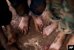 FILE - Displaced Syrian children gather barefoot in a refugee camp near Atma, Idlib province, Syria.