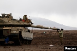 An Israeli soldier sits atop a tank and his comrade stands nearby in the Israeli-occupied Golan Heights, close to Israel's frontier with Syria, Nov. 22, 2017.